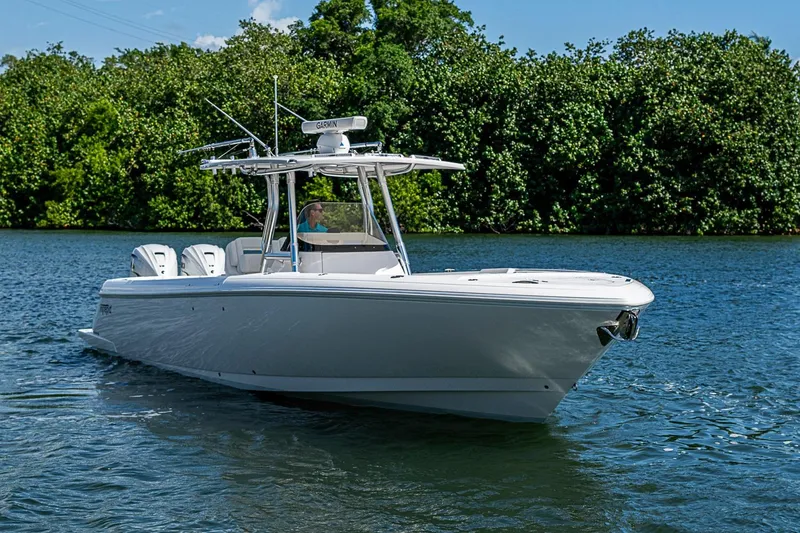 Slide: The Image of 2020 Intrepid 345 Nomad FE boat cruising on a serene lake with lush greenery. - 21