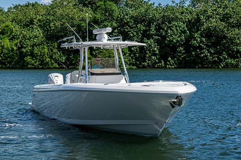 Slide: The Image of 2020 Intrepid 345 Nomad FE boat cruising on a calm lake with lush greenery. - 22