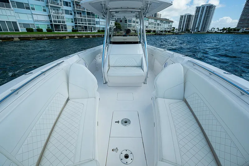 Slide: The Image of 2020 Intrepid 345 Nomad FE boat with luxurious white seating, docked near waterfront buildings. - 30
