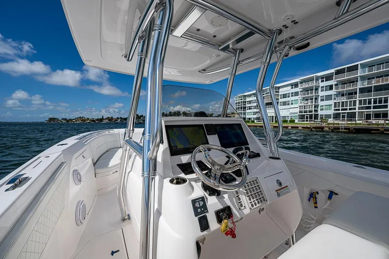 Slide: The Image of 2020 Intrepid 345 Nomad FE boat cockpit with modern controls, on a sunny day by waterfront buildings. - 38