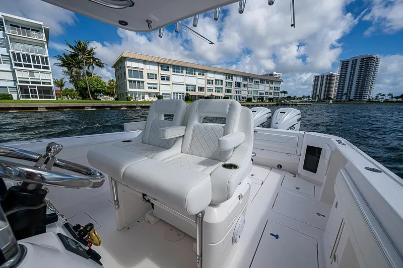 Slide: The Image of 2020 Intrepid 345 Nomad FE boat with luxurious seating, cruising near waterfront buildings. - 39
