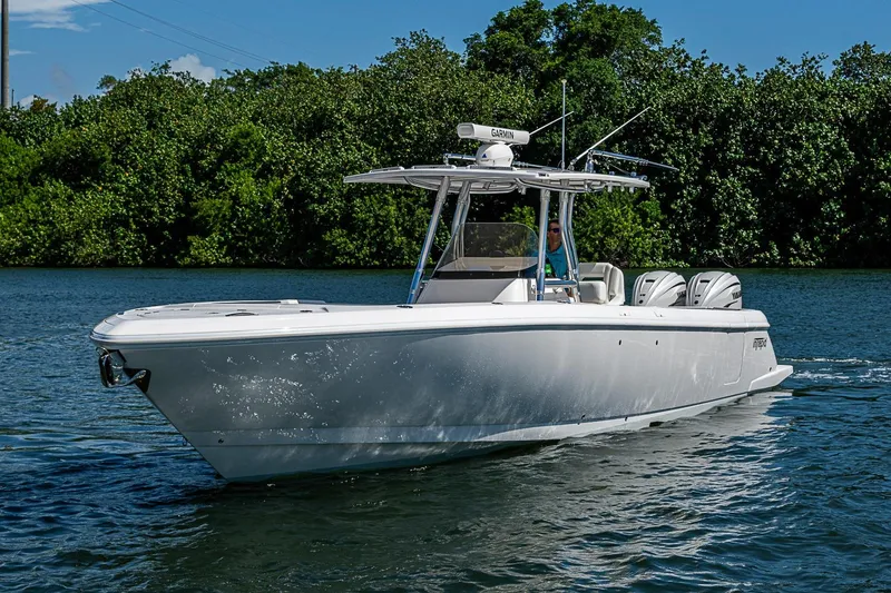 Slide: The Image of 2020 Intrepid 345 Nomad FE boat cruising on a sunny day, surrounded by lush greenery. - 4