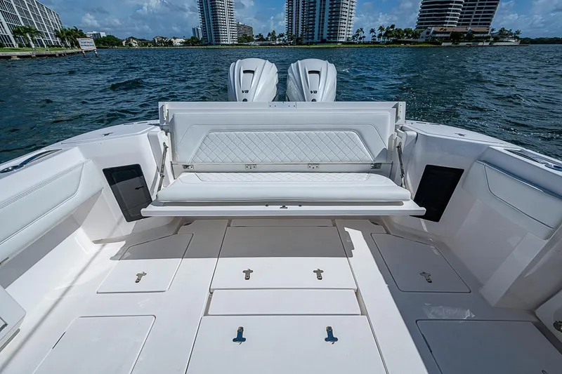Slide: The Image of 2020 Intrepid 345 Nomad FE boat with seating and storage, docked by waterfront buildings. - 43