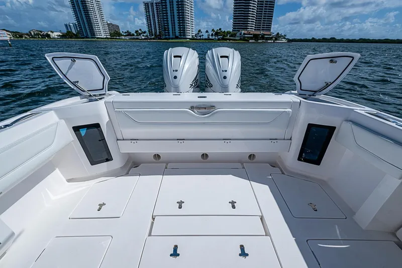 Slide: The Image of 2020 Intrepid 345 Nomad FE boat deck with open storage, twin engines, and waterfront view. - 44