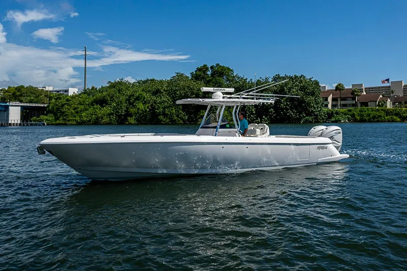Slide: The Image of 2020 Intrepid 345 Nomad FE boat cruising on a sunny day, surrounded by lush greenery. - 5