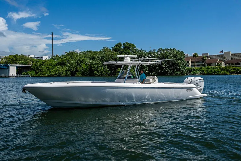 Slide: The Image of 2020 Intrepid 345 Nomad FE boat cruising on a sunny day, surrounded by lush greenery. - 7