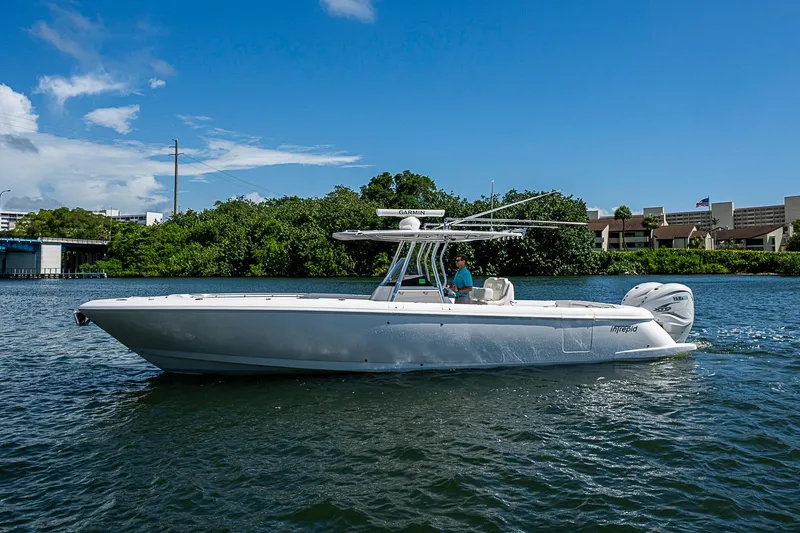 Slide: The Image of 2020 Intrepid 345 Nomad FE boat cruising on a sunny day near lush greenery. - 8