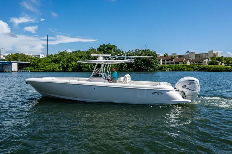 Slide: The Image of 2020 Intrepid 345 Nomad FE boat cruising on a sunny day near lush greenery. - 9