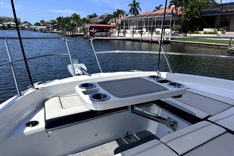Slide: The Image of 2022 Jeanneau Leader 12.5 WA boat with seating and table, docked by waterfront homes. - 10