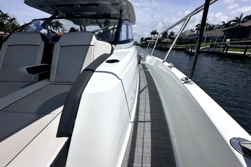 Slide: The Image of 2022 Jeanneau Leader 12.5 WA boat, sleek design, docked by waterfront homes. - 12