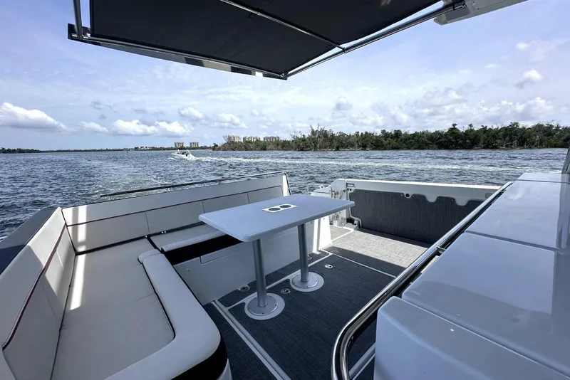 Slide: The Image of 2022 Jeanneau Leader 12.5 WA boat interior with seating and table, overlooking serene waters. - 16