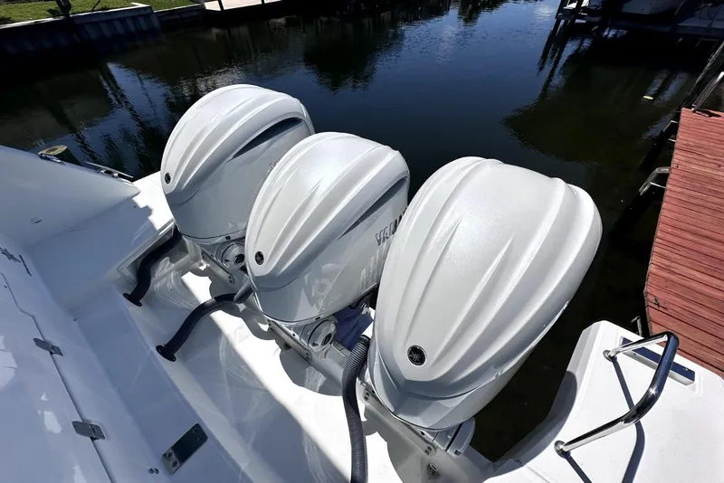 Slide: The Image of Triple outboard engines on a 2022 Jeanneau Leader 12.5 WA boat docked by water. - 33