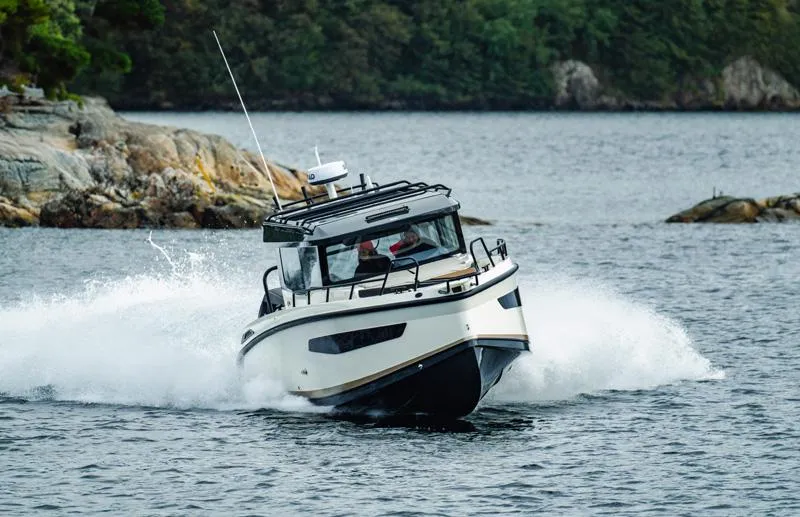 Slide: The Image of Navan C30 2025 boat navigating through water near rocky shoreline. - 1