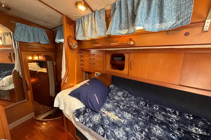 Slide: The Image of Cozy cabin interior of 1980 Amel Mango 52 sailboat with wooden furnishings and blue curtains. - 50