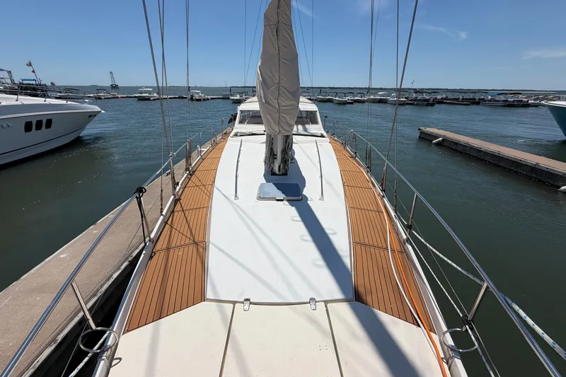 Slide: The Image of 1980 Amel Mango 52 sailboat docked at marina, featuring teak deck and clear blue sky. - 16