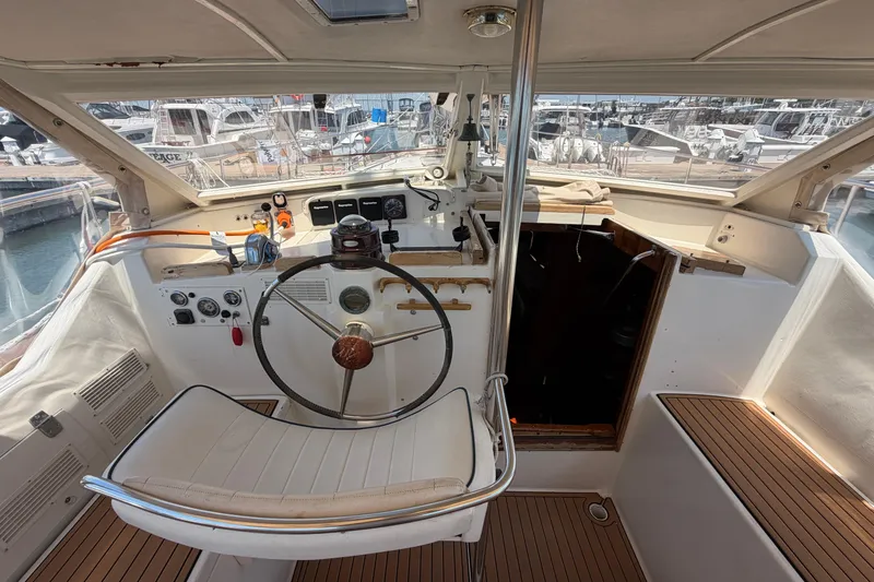 Slide: The Image of Cockpit of 1980 Amel Mango 52 sailboat with steering wheel and marina view. - 33
