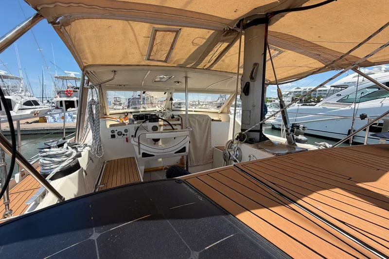 Slide: The Image of Cockpit of 1980 Amel Mango 52 sailboat with wooden deck and marina view. - 27