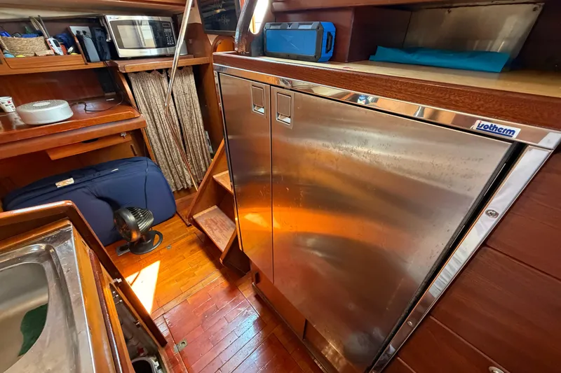 Slide: The Image of Interior of 1980 Amel Mango 52 yacht with stainless steel fridge and wooden cabinetry. - 43