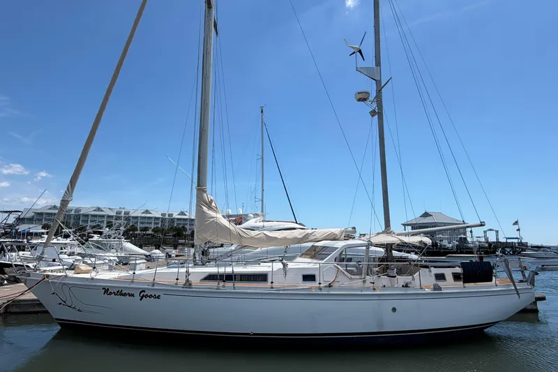 The Image of 1980 Amel Mango 52 sailboat docked at marina under clear blue sky. - 1