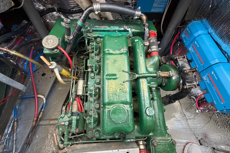 Slide: The Image of Engine compartment of a 1980 Amel Mango 52 sailboat, featuring a green marine engine. - 61