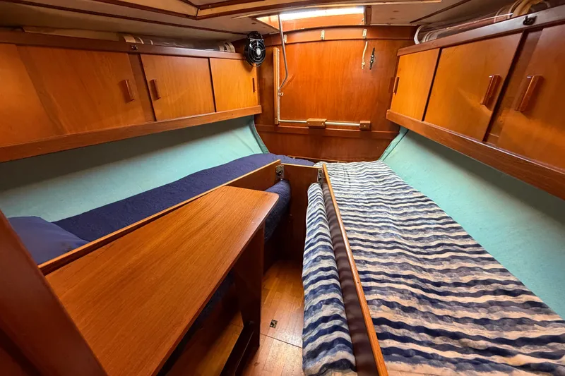 Slide: The Image of Interior of 1980 Amel Mango 52 sailboat with wooden cabinetry and twin beds. - 53