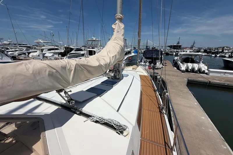 Slide: The Image of 1980 Amel Mango 52 sailboat docked at a marina under a clear blue sky. - 11
