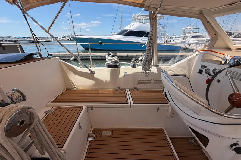 Slide: The Image of Cockpit of 1980 Amel Mango 52 sailboat with wooden flooring, docked at marina. - 28