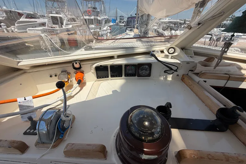 Slide: The Image of Cockpit of 1980 Amel Mango 52 sailboat with navigation instruments and marina view. - 34