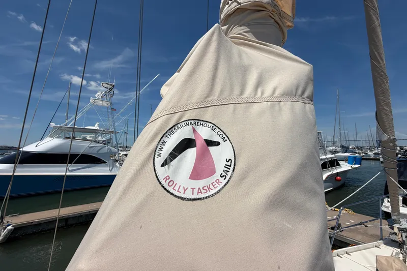 Slide: The Image of Sail cover on Amel Mango 52 yacht, featuring Rolly Tasker Sails logo at marina. - 21