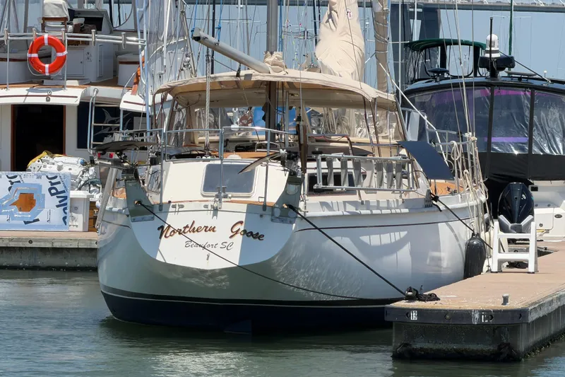 Slide: The Image of 1980 Amel Mango 52 sailboat docked at marina, named "Northern Goose," with surrounding boats. - 8