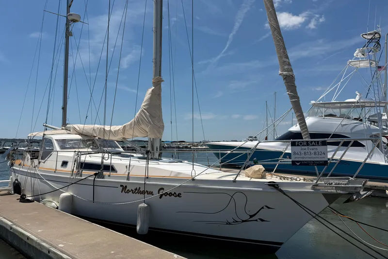 Slide: The Image of Sailboat Amel Mango 52, 1980 model, docked with "For Sale" sign, clear sky background. - 7