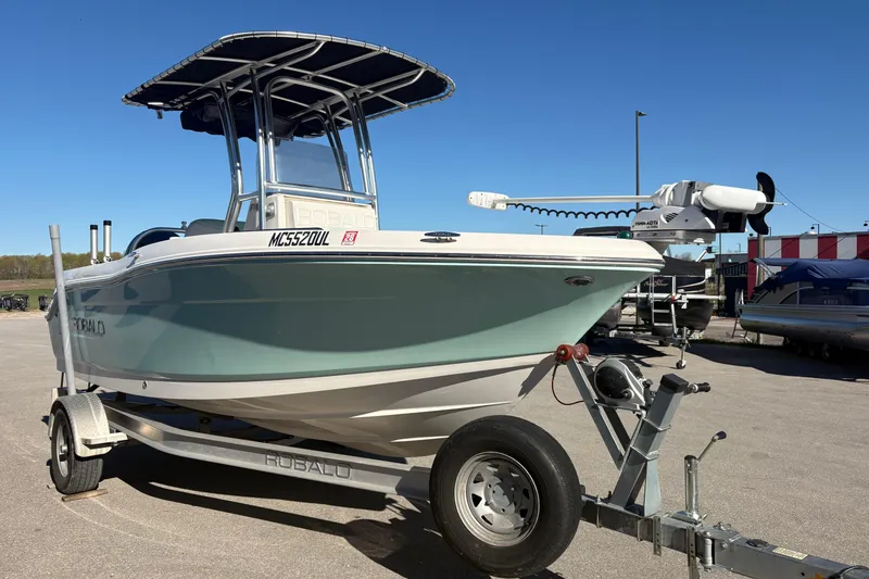 Slide: The Image of 2019 Robalo R180 Center Console boat on trailer, parked outdoors under clear blue sky. - 2