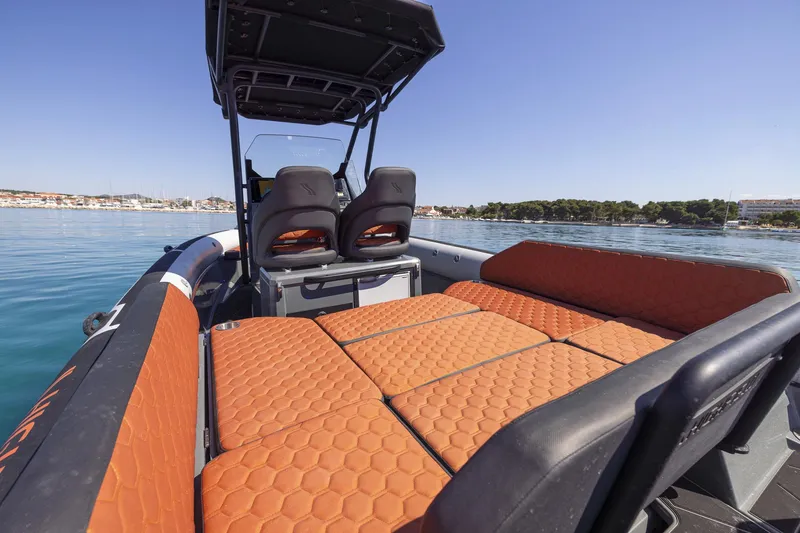 Slide: The Image of 2026 Highfield ADV7 boat with orange seating, on calm water under clear blue sky. - 6