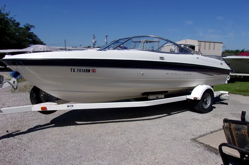The Image of 2003 Bayliner 205 boat on trailer, parked outdoors under clear blue sky. - 1