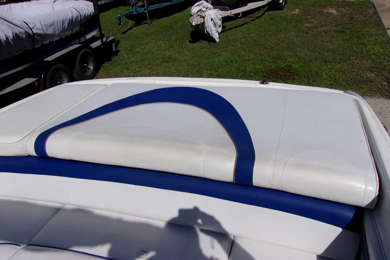 Slide: The Image of 2003 Bayliner 205 boat interior with white and blue upholstery, parked on grass. - 10