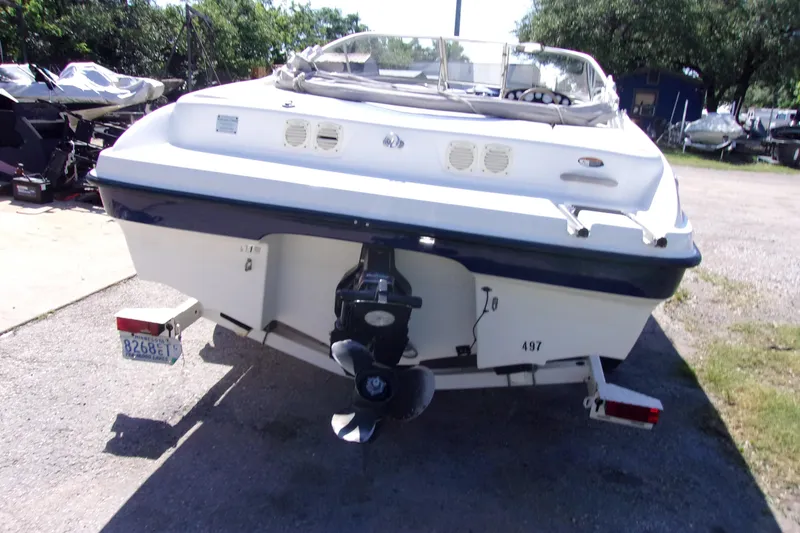 Slide: The Image of 2003 Bayliner 205 boat rear view, parked on a trailer in a sunny outdoor setting. - 3