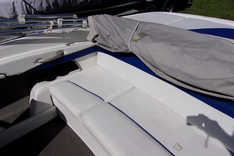 Slide: The Image of 2003 Bayliner 205 boat interior with white seating and covered equipment. - 9