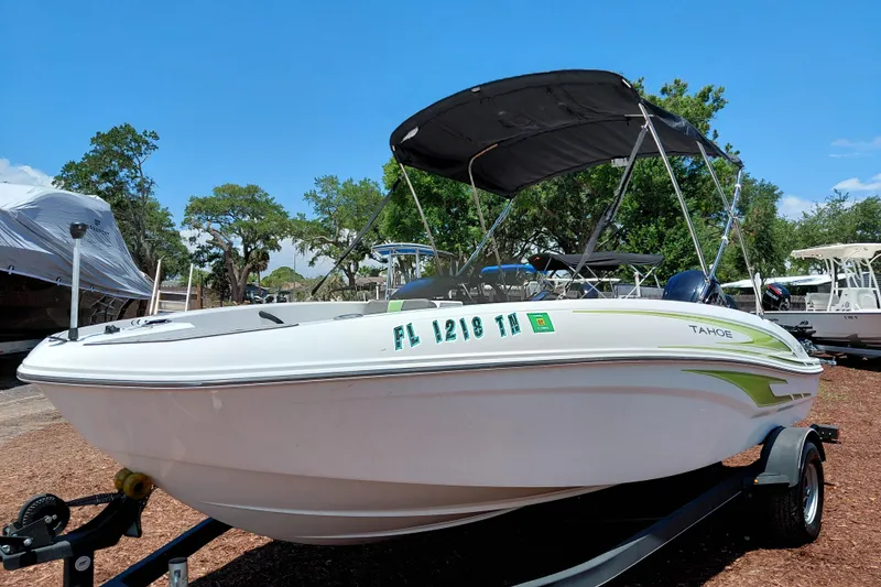 Slide: The Image of 2023 Tahoe T18 boat with canopy on trailer, parked outdoors under clear blue sky. - 4
