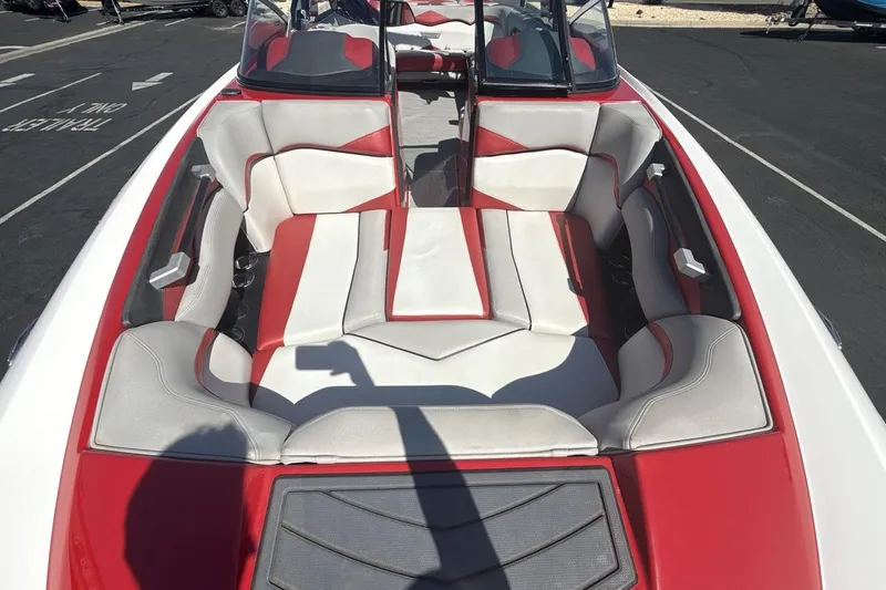 Slide: The Image of 2016 Supra SE 550 boat interior with red and white seating, parked on asphalt. - 12