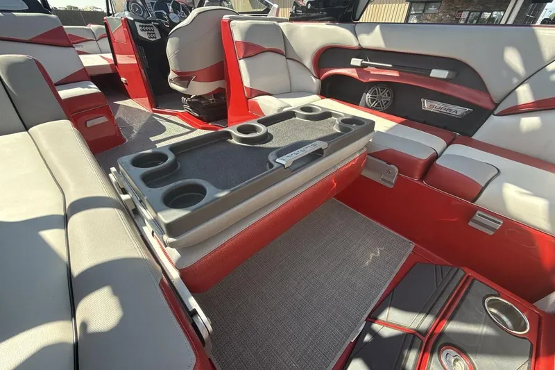 Slide: The Image of 2016 Supra SE 550 boat interior with red and gray seating, cup holders, and speaker system. - 23