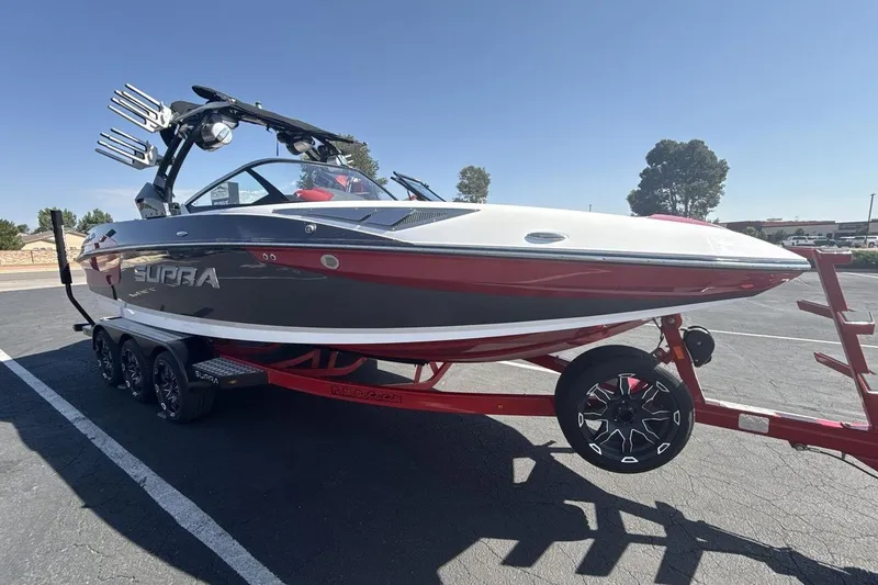 Slide: The Image of 2016 Supra SE 550 boat on trailer, sleek design, red and white color scheme, parked outdoors. - 7