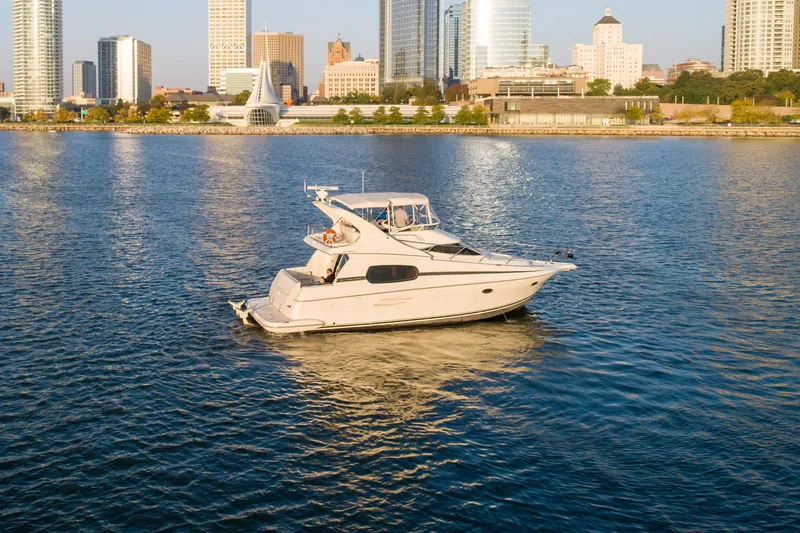 Slide: The Image of 2003 Silverton 410 Sport Bridge yacht on calm water with city skyline backdrop. - 12