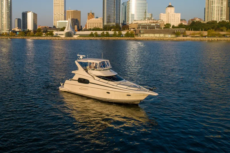 Slide: The Image of 2003 Silverton 410 Sport Bridge yacht on calm water with city skyline backdrop. - 18