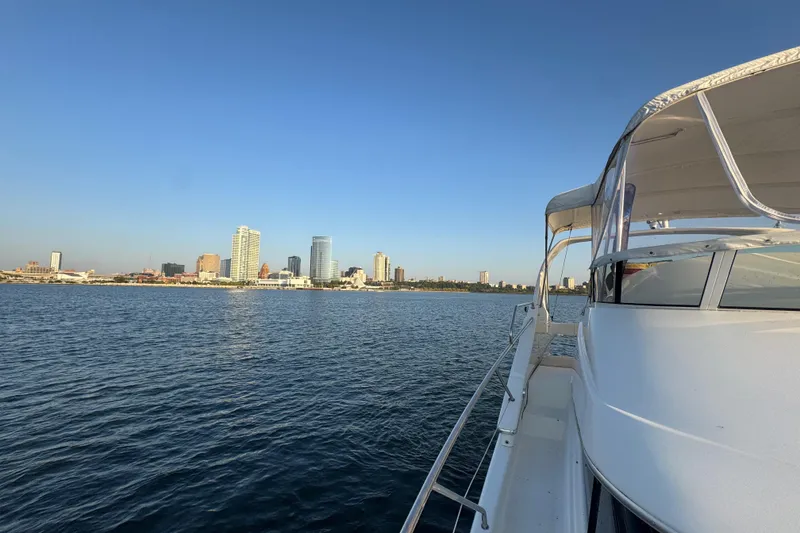 Slide: The Image of 2003 Silverton 410 Sport Bridge yacht cruising near city skyline on calm water. - 36