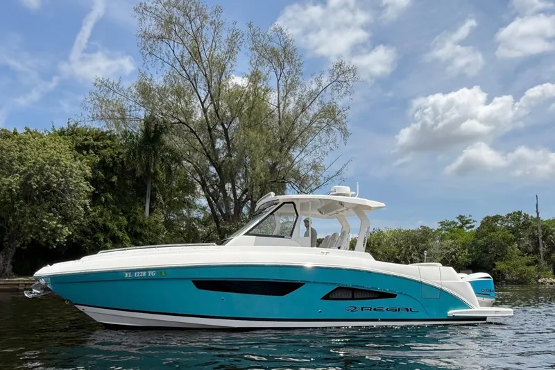 The Image of 2021 Regal 33 SAV boat on water, surrounded by lush greenery and clear skies. - 0