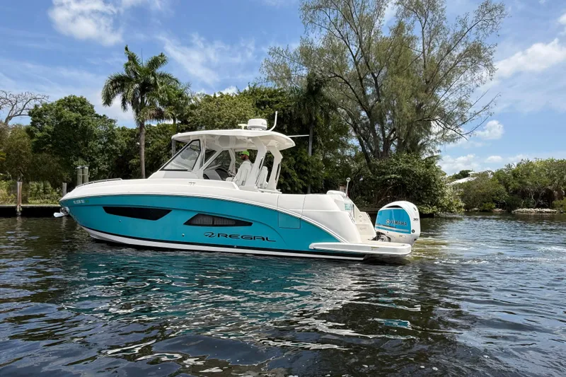 Slide: The Image of 2021 Regal 33 SAV boat on a scenic waterway with lush greenery. - 1