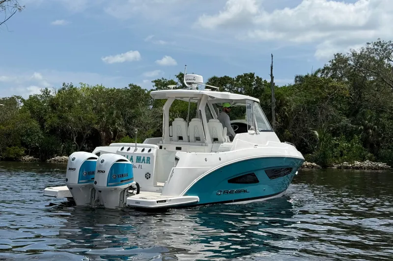 Slide: The Image of 2021 Regal 33 SAV boat with twin Yamaha engines on a scenic waterway. - 2