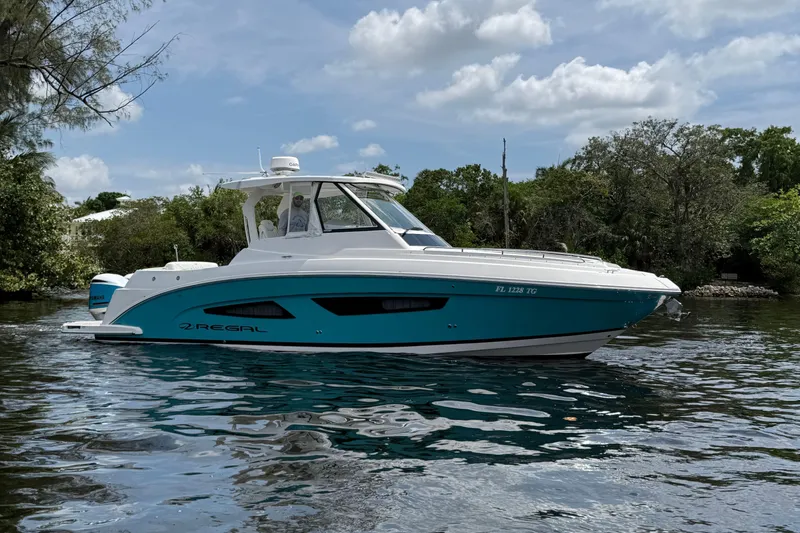 Slide: The Image of 2021 Regal 33 SAV boat cruising on a calm river under a partly cloudy sky. - 3