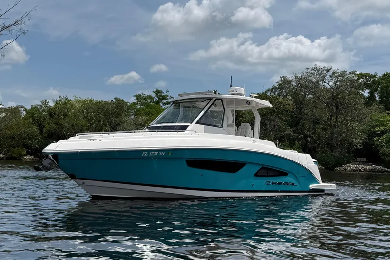 Slide: The Image of 2021 Regal 33 SAV boat on a calm river under a partly cloudy sky. - 4