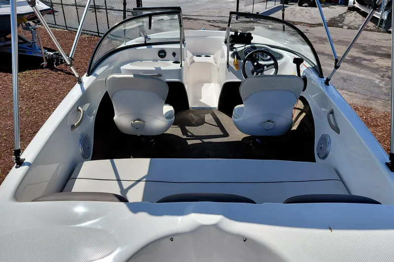 Slide: The Image of 2021 Bayliner 160 Bowrider interior with seating and steering wheel, parked outdoors. - 30